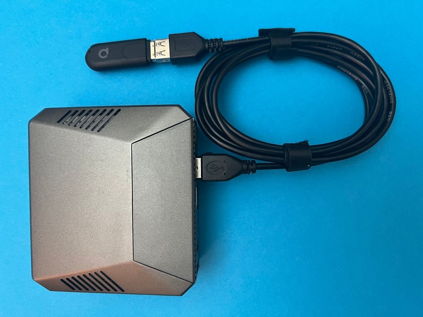 A ConBee II Zigbee gateway plugged into a Raspberry Pi 4 case via a USB extension cable